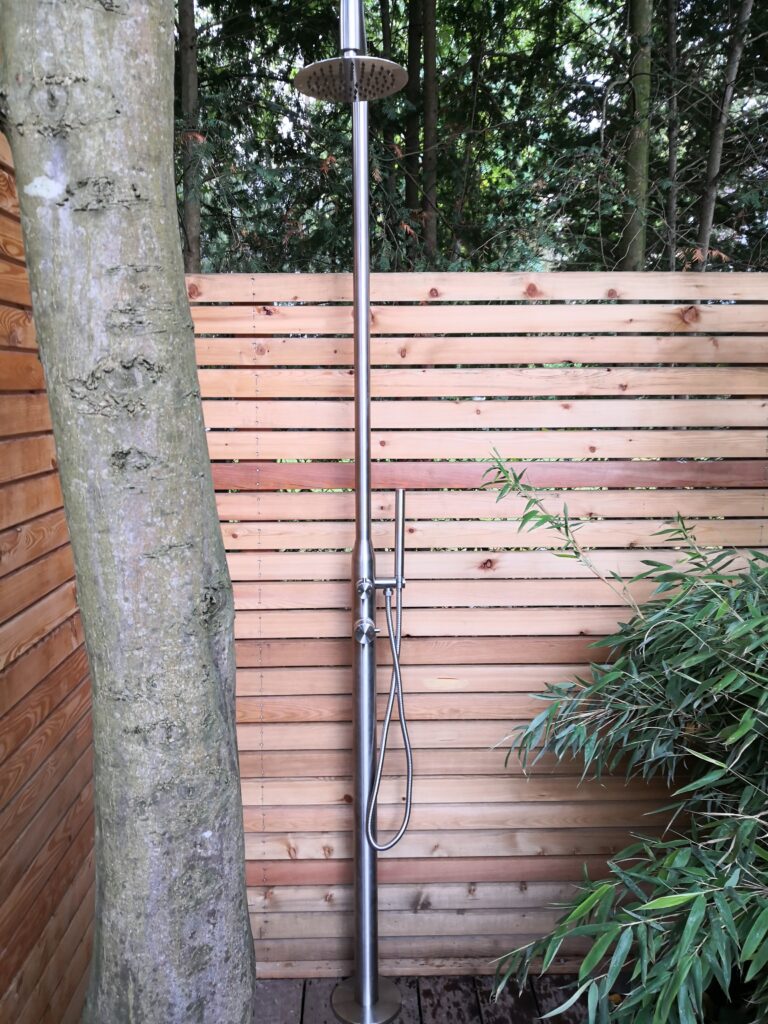 Außendusche im Garten vor Holzsichtschutz als Teil einer Gartengestaltung in Bad Segeberg